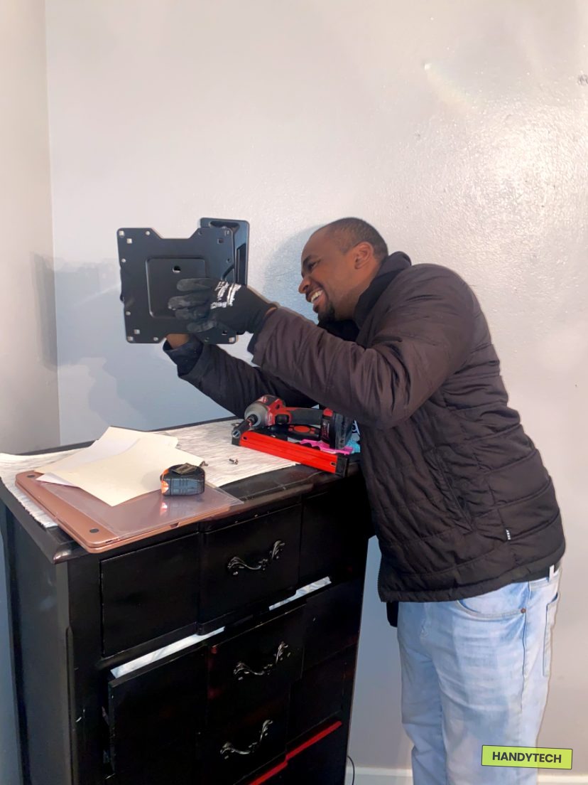 HandyTech LLC Hattiesburg owner mounting a TV bracket plate on a piece of furniture